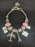 Pink Jetsetter Travel Charm Bracelet close-up with airplane and Eiffel Tower charms