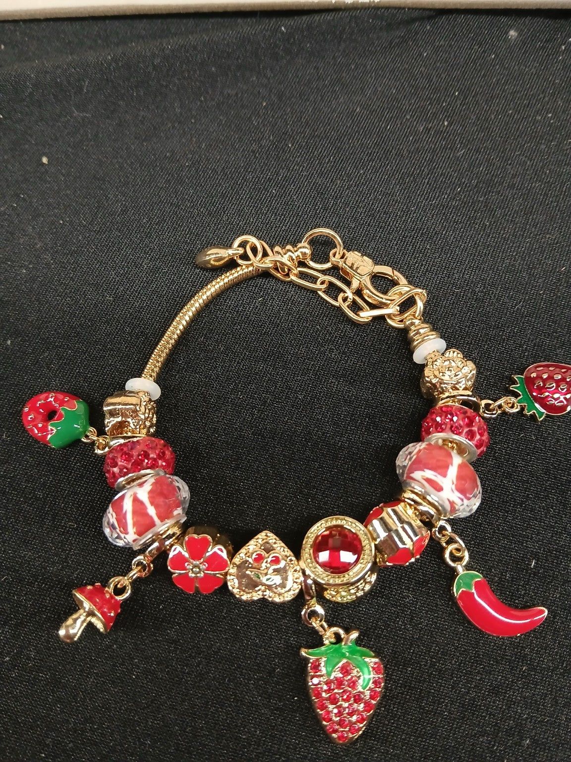 Close-up red and gold strawberry spice charm bracelet